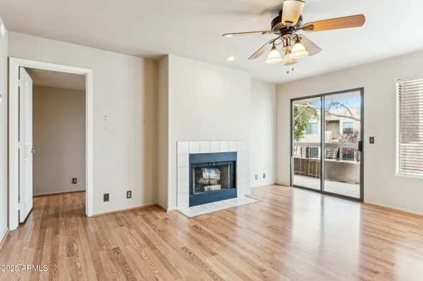 a view of an empty room with wooden floor fireplace and a window
