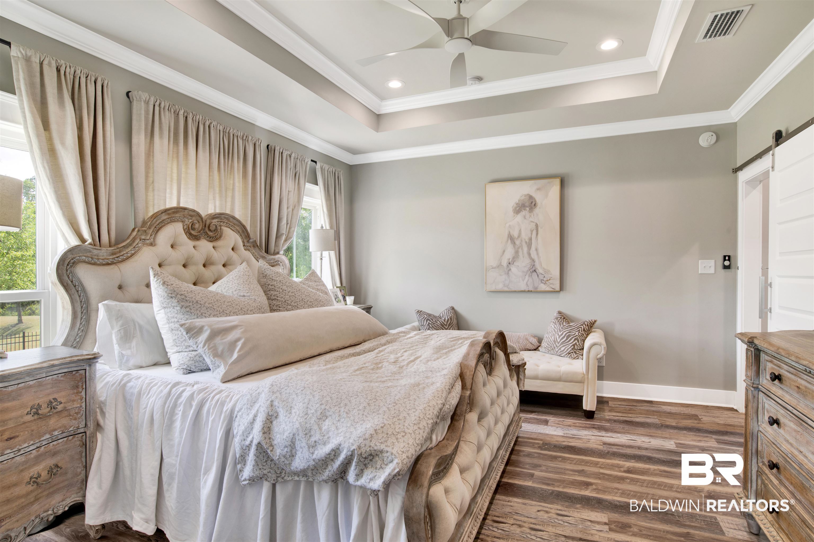 21621 Veranda Boulevard Fairhope, AL 36532 - Photo 16 of 51 Bedroom with visible vents, crown molding, a barn door, a raised ceiling, and dark wood-style floors