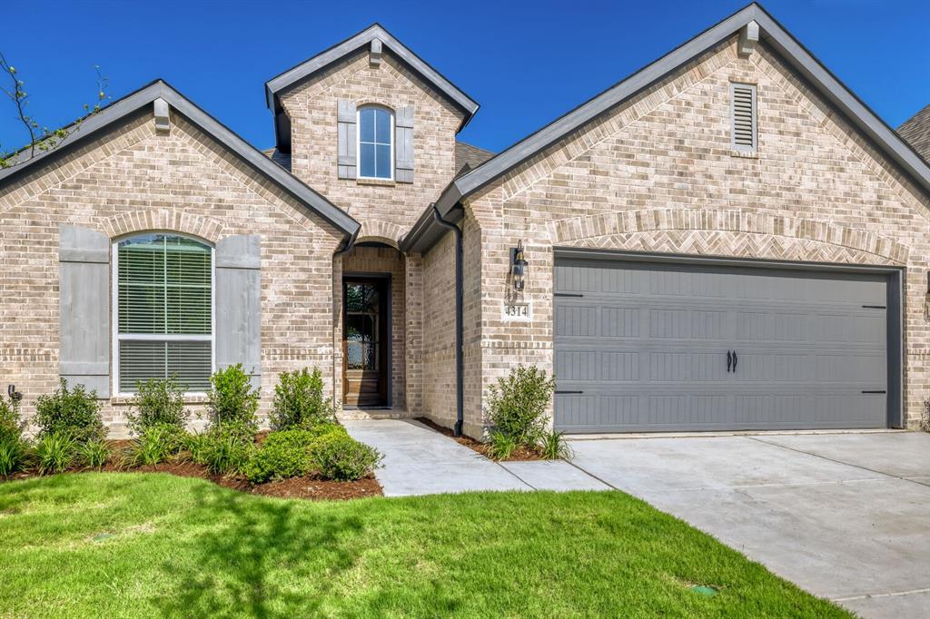 4314 Haley Way Oak Point, TX 75068 - Photo 28 of 28 Brick exterior with a prominent arched entry, attached garage with decorative hardware, and architectural rooflines