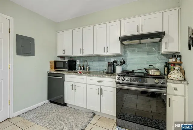 a kitchen with stainless steel appliances granite countertop a stove a sink and white cabinets