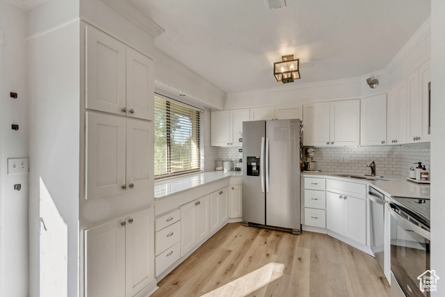 360 East Center Street Centerville, UT 84014 - Photo 12 of 41 Kitchen featuring appliances with stainless steel finishes, white cabinetry, light wood-style flooring, decorative backsplash, and crown molding