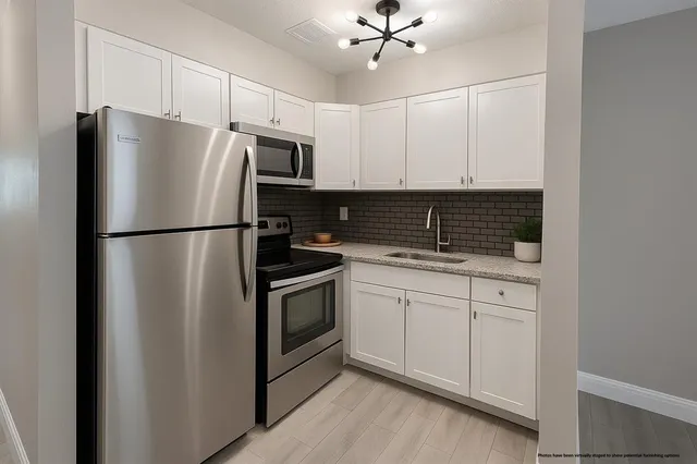 a kitchen with stainless steel appliances granite countertop a refrigerator a stove a sink and white cabinets