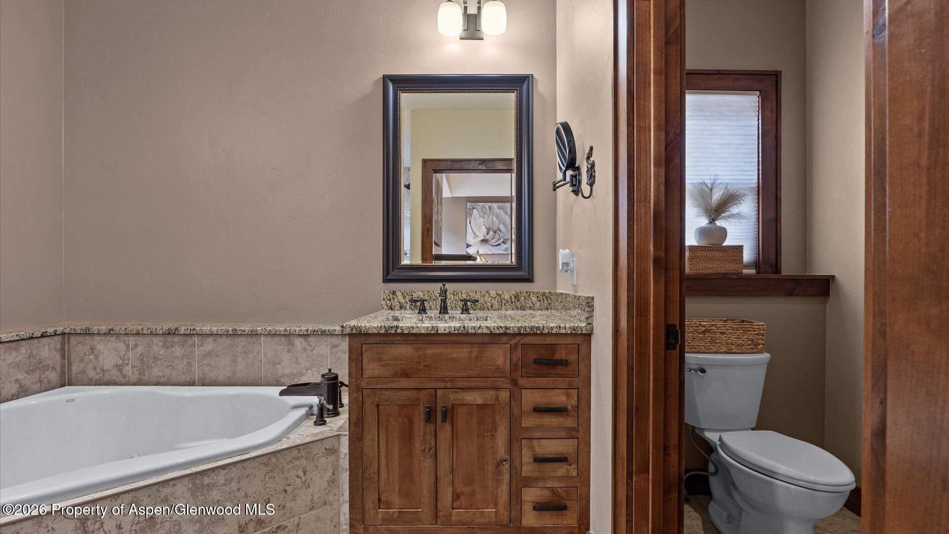 829 Ute Circle New Castle, CO 81647 - Photo 16 of 37 a bathroom with a granite countertop toilet a sink and bathtub