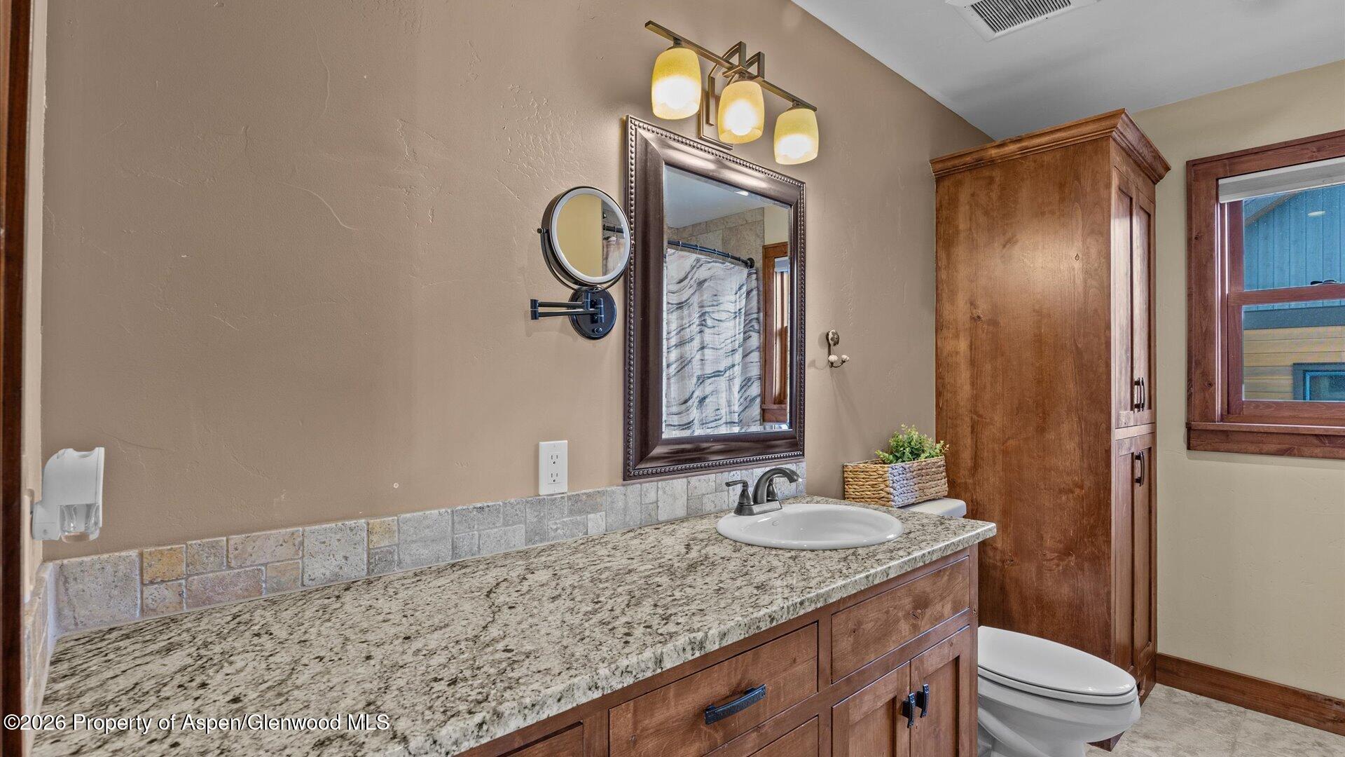 829 Ute Circle New Castle, CO 81647 - Photo 25 of 37 a bathroom with a granite countertop sink a toilet and a mirror