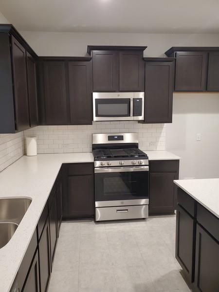 6404 Gunflint Drive Austin, TX 78747 - Photo 4 of 21 A contemporary kitchen features dark cabinetry, light countertops, and stainless steel appliances.