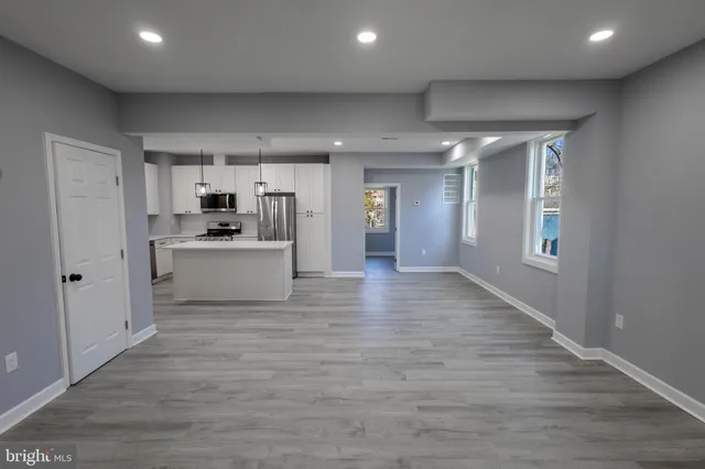 a view of a electric appliances in kitchen and empty room with wooden floor