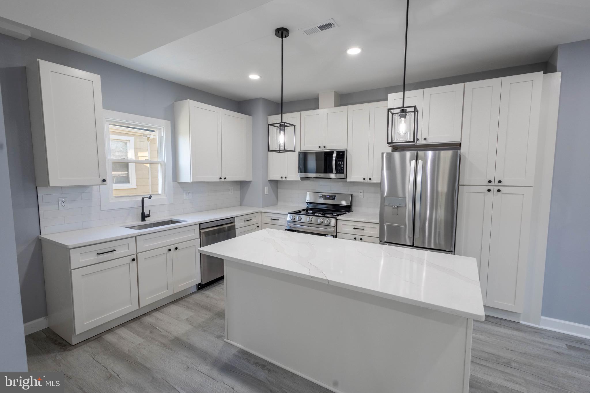 619 Aldershot Road Baltimore, MD 21229 - Photo 8 of 29 a kitchen with stainless steel appliances kitchen island a refrigerator sink and white cabinets