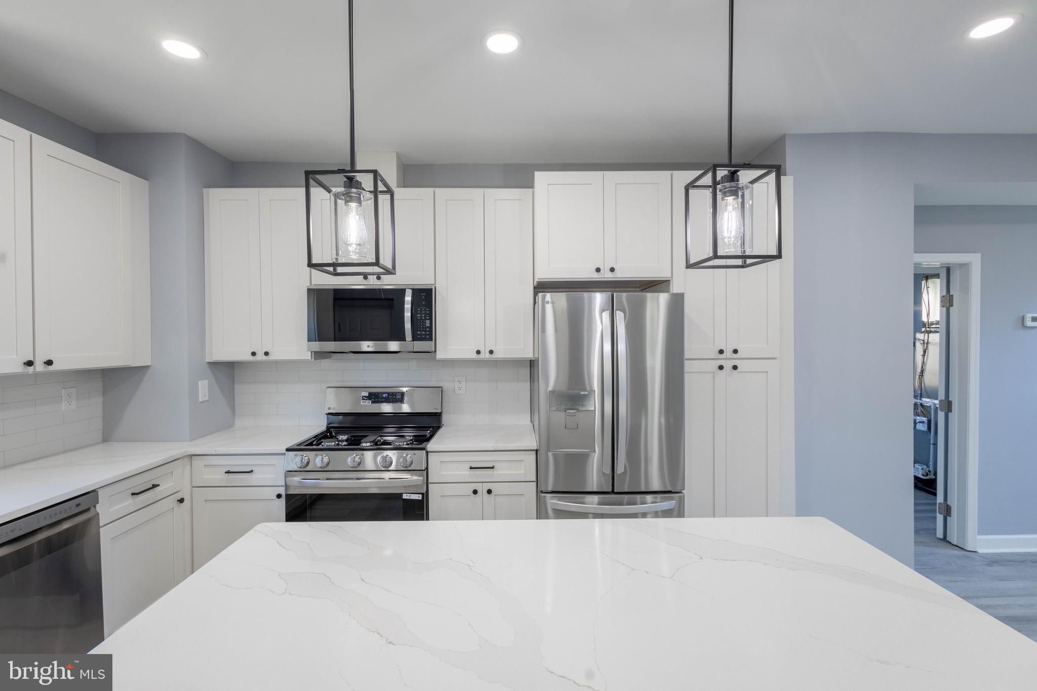 619 Aldershot Road Baltimore, MD 21229 - Photo 9 of 29 a kitchen with stainless steel appliances kitchen island granite countertop a refrigerator a stove and white cabinets