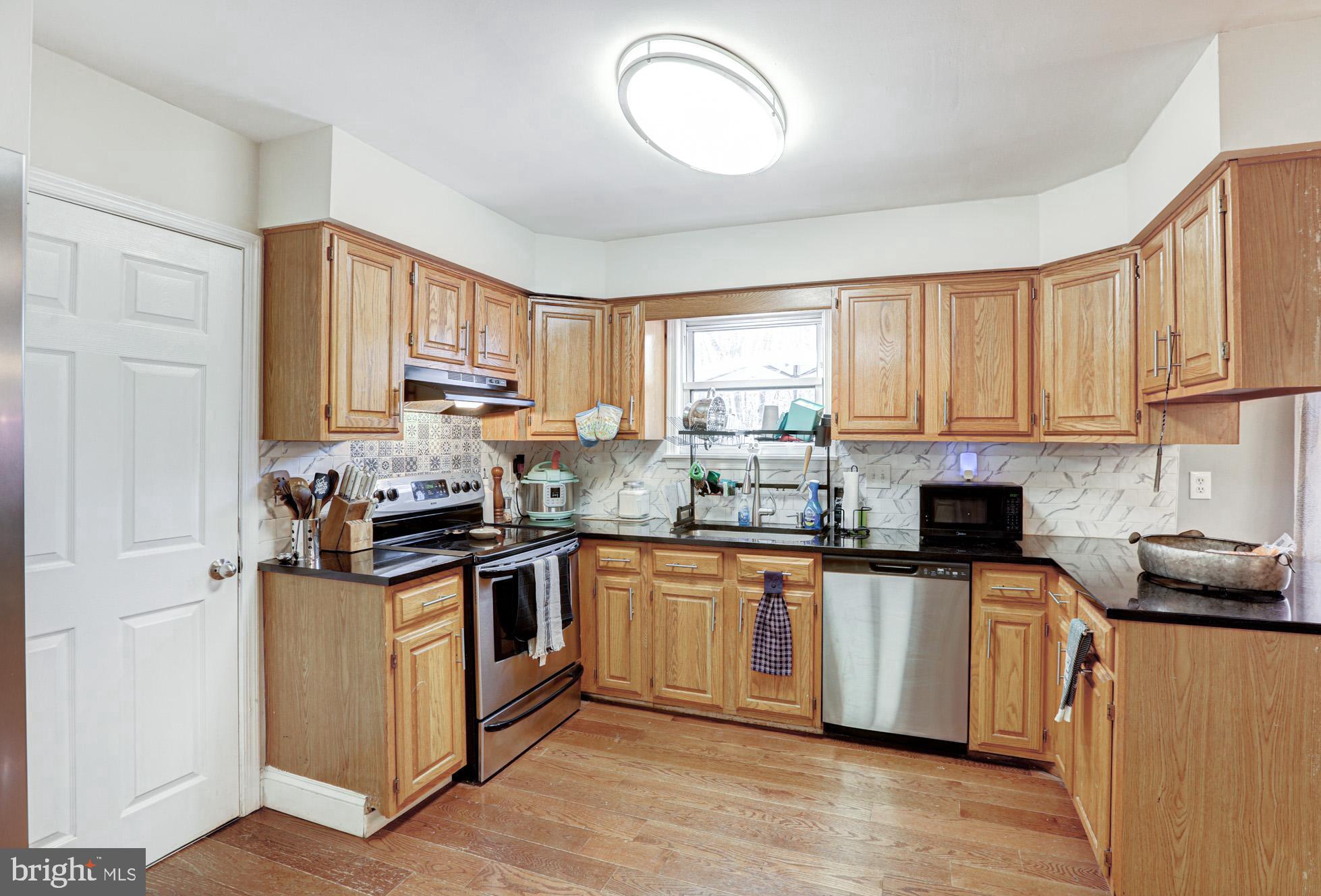 15 Evergreen Drive Newark, DE 19702 - Photo 26 of 85 a kitchen with stainless steel appliances granite countertop white cabinets a stove top oven a sink and dishwasher with wooden floor