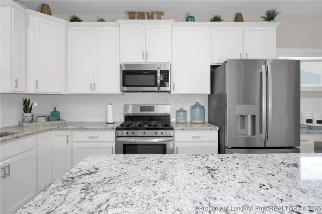 a kitchen with stainless steel appliances granite countertop a refrigerator stove top oven and sink