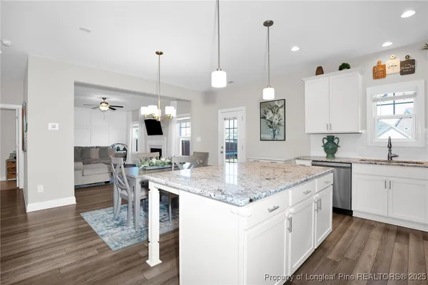 a kitchen with kitchen island granite countertop a sink cabinets and wooden floor