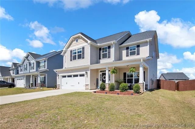 a view of a white house with a large yard and large tree