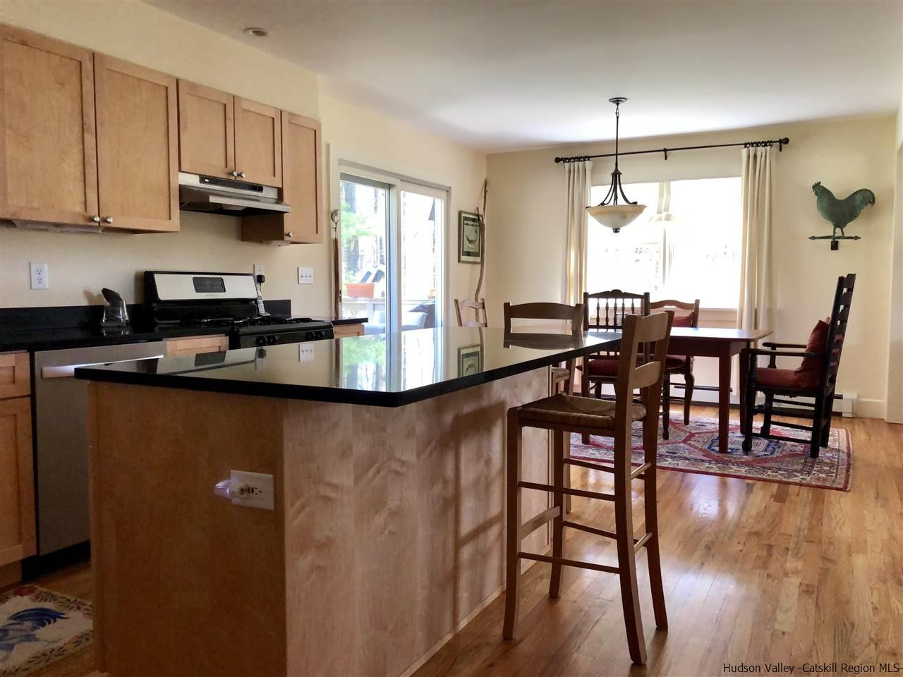 52 Buck Road Stone Ridge, NY 12484 - Photo 6 of 35 a kitchen with stainless steel appliances granite countertop a stove a refrigerator a dining table and chairs with wooden floor