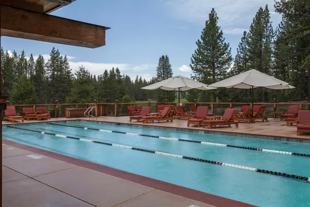 a view of a swimming pool with lawn chairs under an umbrella