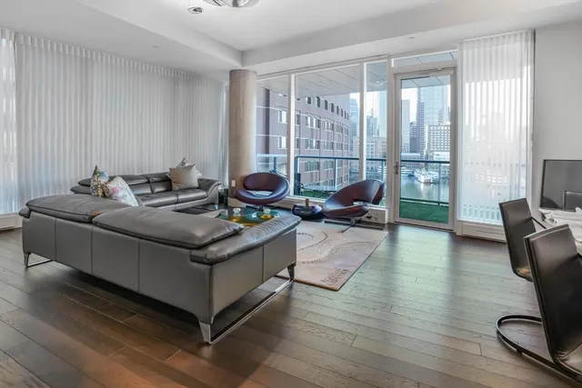a living room with furniture hard wood floor and a floor to ceiling window