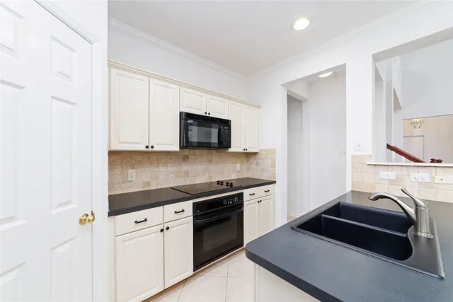 a kitchen with kitchen island granite countertop a sink and a stove top oven with white cabinets