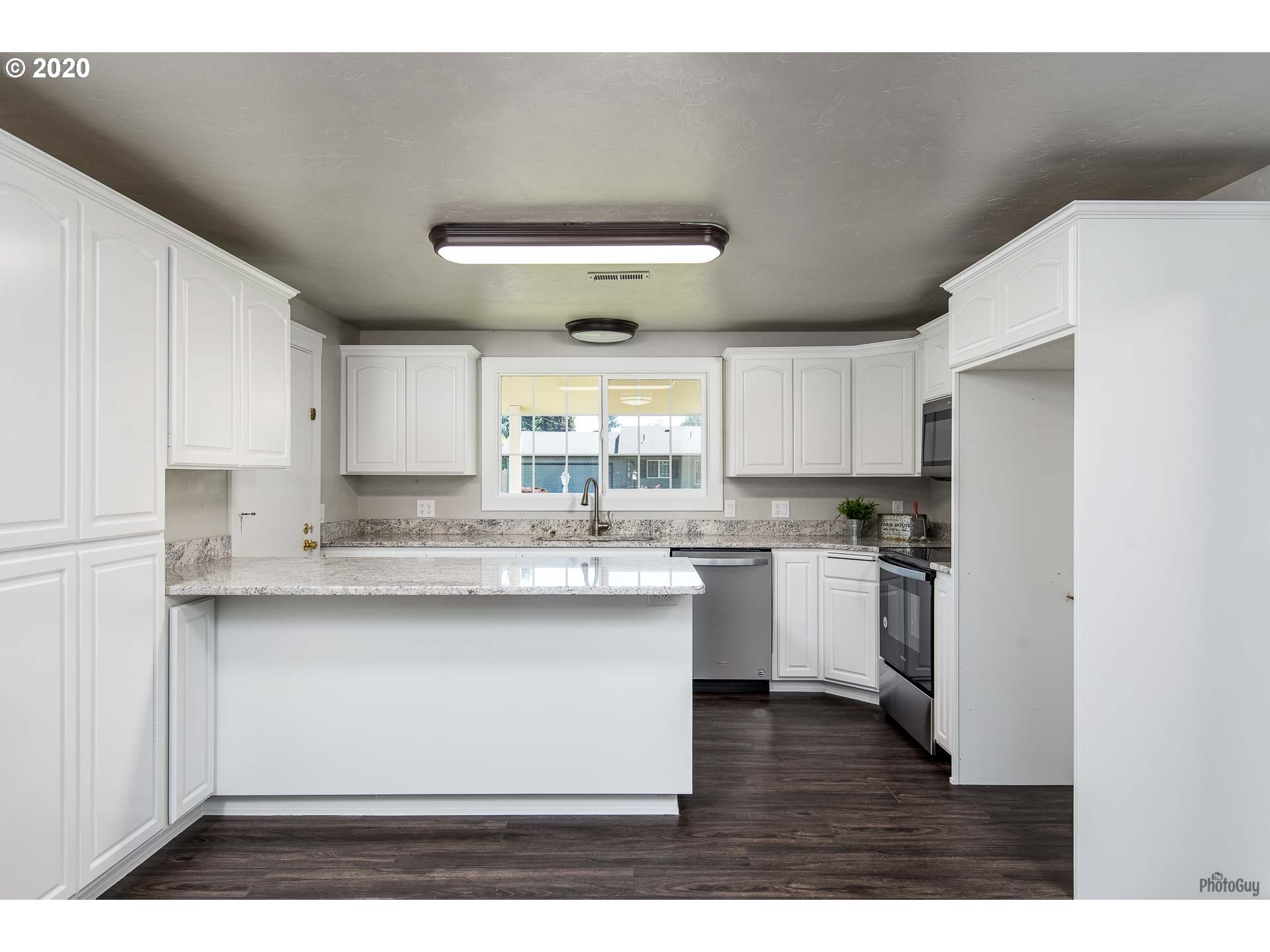 2470 North 14th Place Springfield, OR 97477 - Photo 9 of 32 a kitchen with stainless steel appliances granite countertop a sink a stove a refrigerator with white cabinets and wooden floor