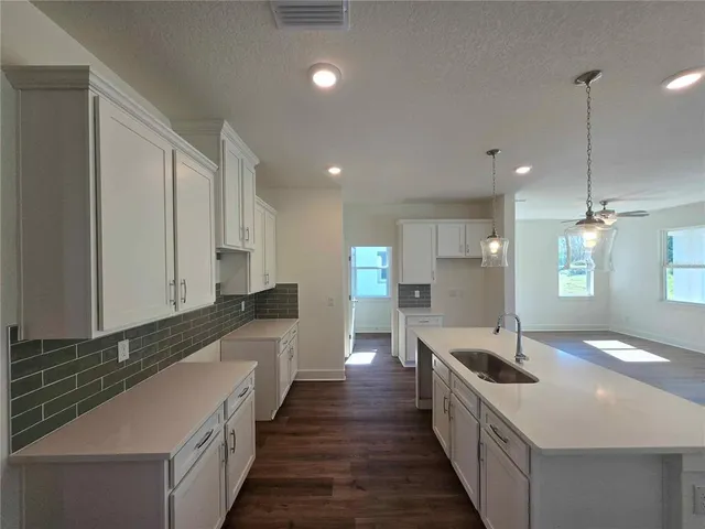 a large kitchen with stainless steel appliances a sink and a wooden floors