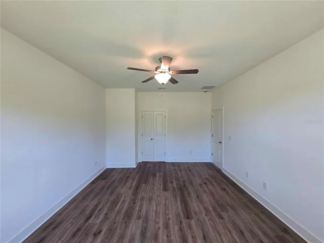 a view of a room with wooden floor and a ceiling fan