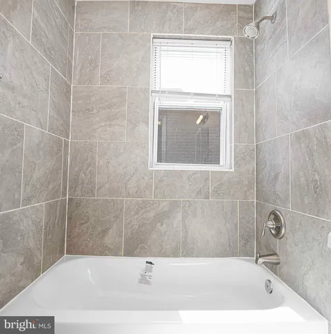 a bathroom with a tub a window and vanity