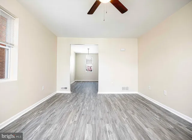 an empty room with wooden floor cabinet and windows