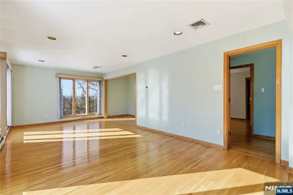 a view of an empty room with window and wooden floor