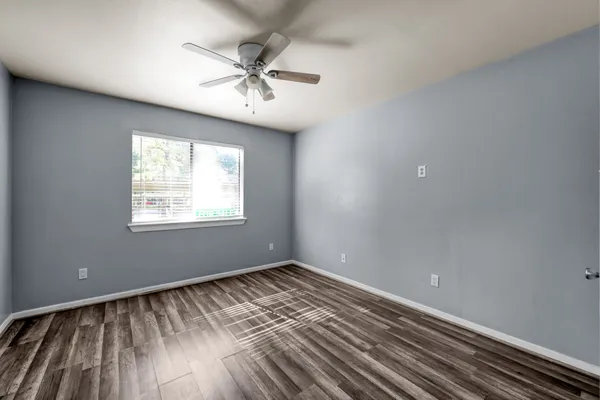 a view of an empty room with wooden floor and a window