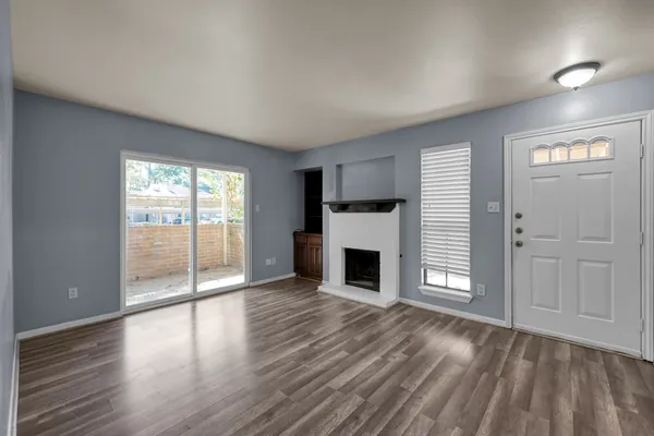 an empty room with wooden floor a fireplace and windows