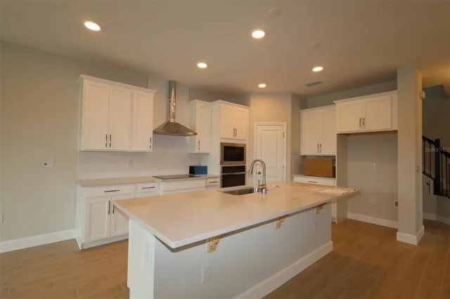 a kitchen with a sink a stove a refrigerator and white cabinets