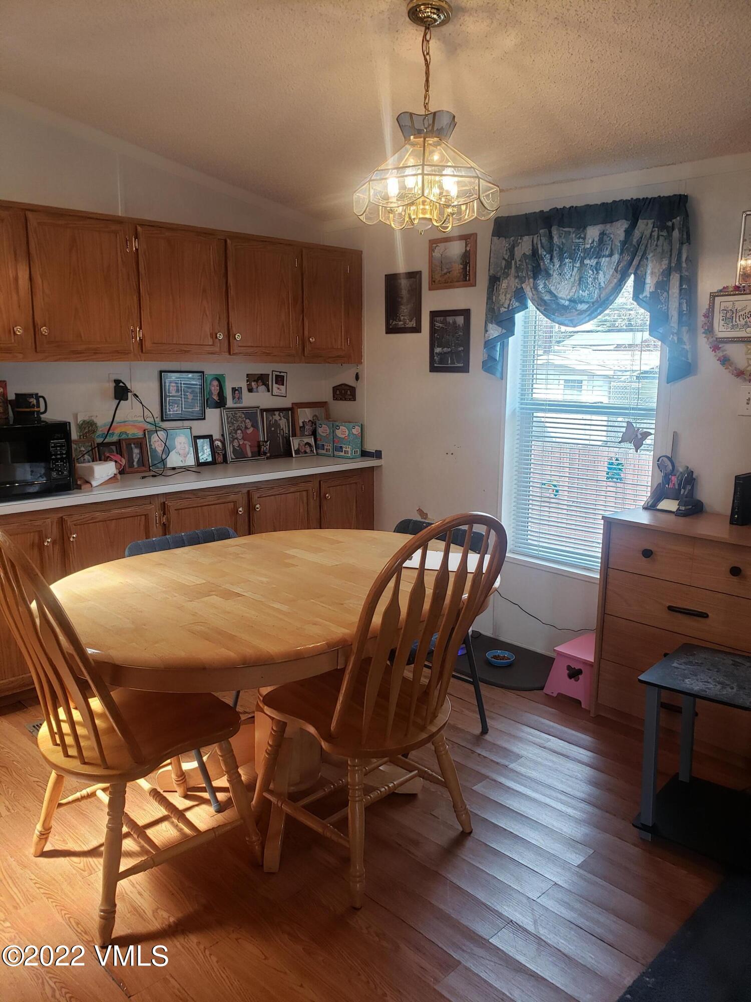 742 2nd Street Gypsum, CO 81637 - Photo 5 of 17 a dining room with wooden floor a chandelier a wooden table and chairs