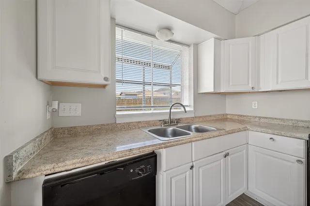 a kitchen with granite countertop a sink and white cabinets