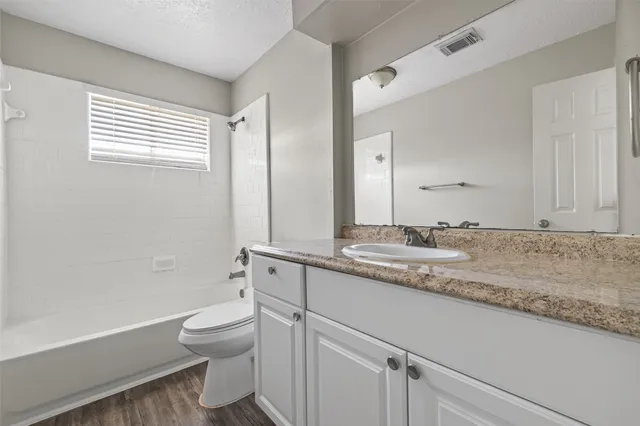 a bathroom with a granite countertop sink a toilet and a bathtub