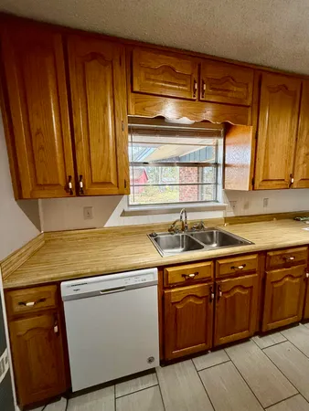 a utility room with stainless steel appliances wooden cabinets and a sink