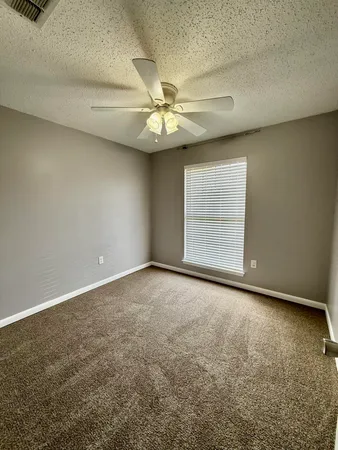 an empty room with windows and fan