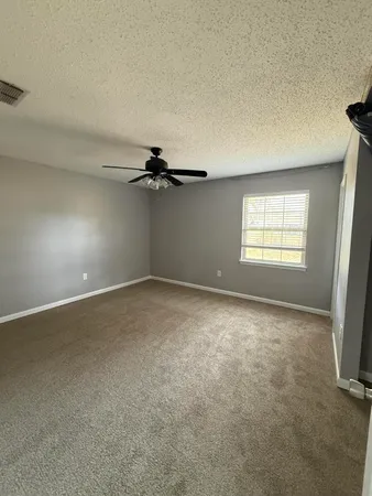 an empty room with windows and fan