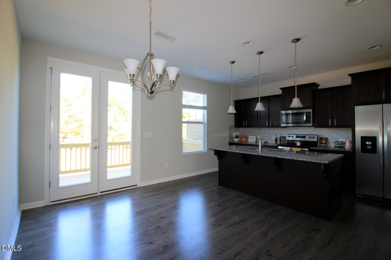 349 Great Northern Station Apex, NC 27502 - Photo 8 of 20 a kitchen with stainless steel appliances granite countertop a refrigerator a sink dishwasher a stove and a dining table with wooden floor