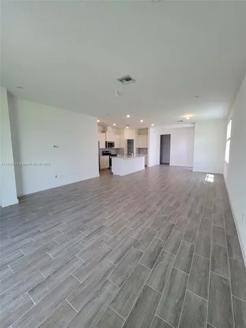 a view of a big room with wooden floor and windows