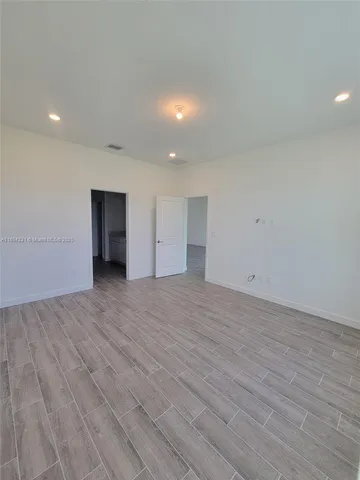 a view of an empty room with wooden floor and closet