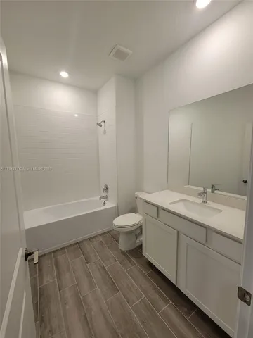 a bathroom with a granite countertop sink toilet a large mirror a bathtub and shower