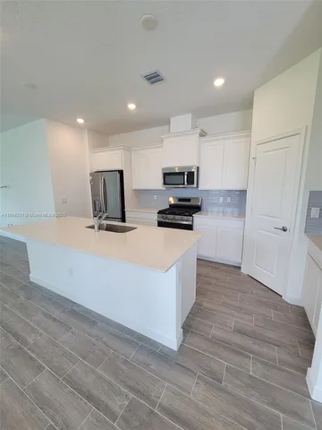 a large white kitchen with wooden floors and stainless steel appliances