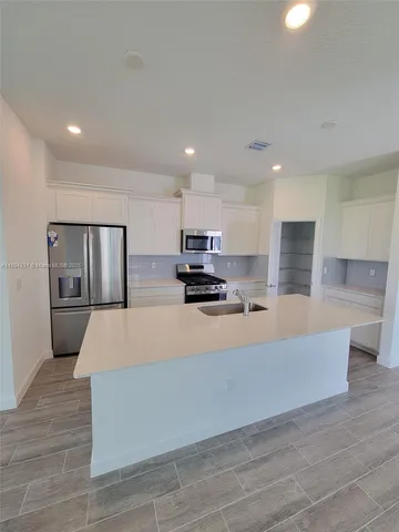 a large white kitchen with kitchen island stainless steel appliances sink and stove