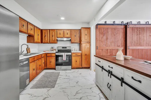 a kitchen with granite countertop a sink a counter top space stainless steel appliances and cabinets