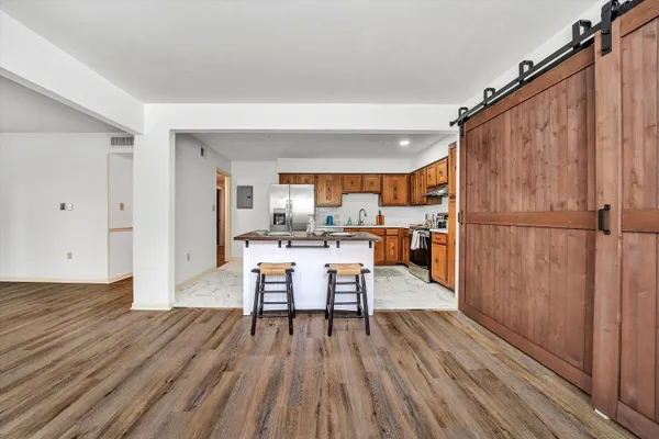 a dining room with wooden floor and a kitchen