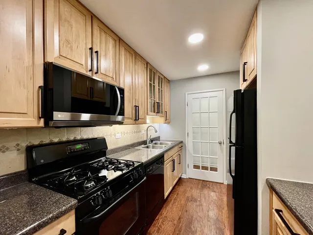 a kitchen with stainless steel appliances granite countertop a stove a sink and a microwave