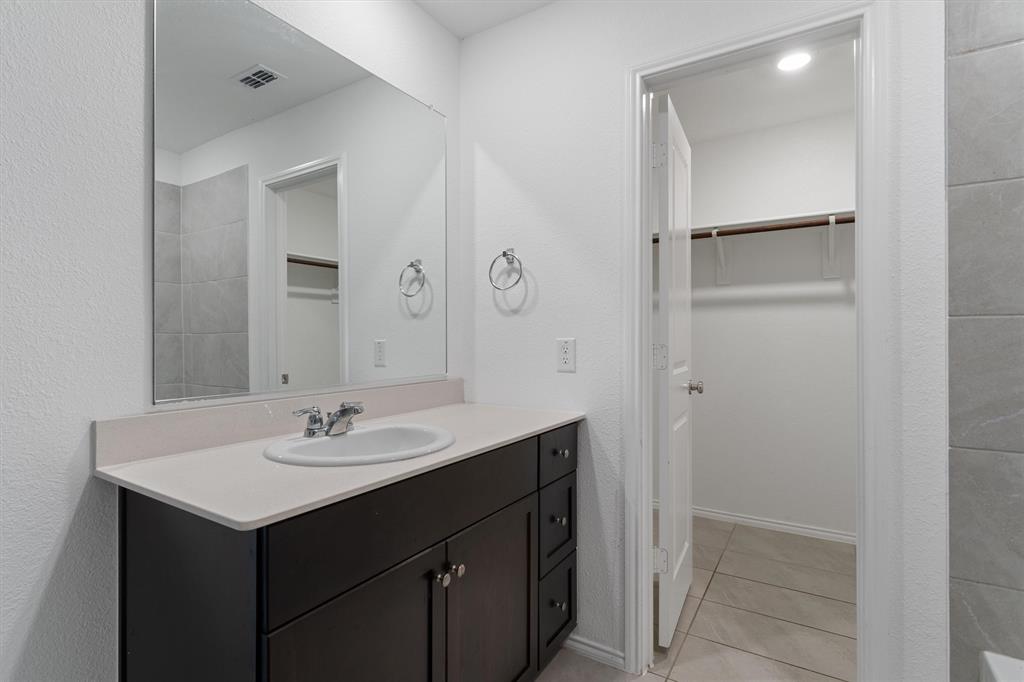 7781 Ruellia Road McKinney, TX 75071 - Photo 14 of 25 Bathroom with vanity, a spacious closet, and tile patterned flooring