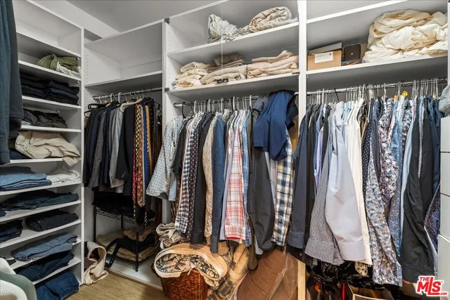 a view of walk in closet with clothes and shoes