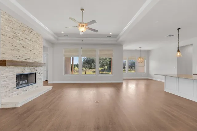 an empty room with wooden floor fireplace and windows