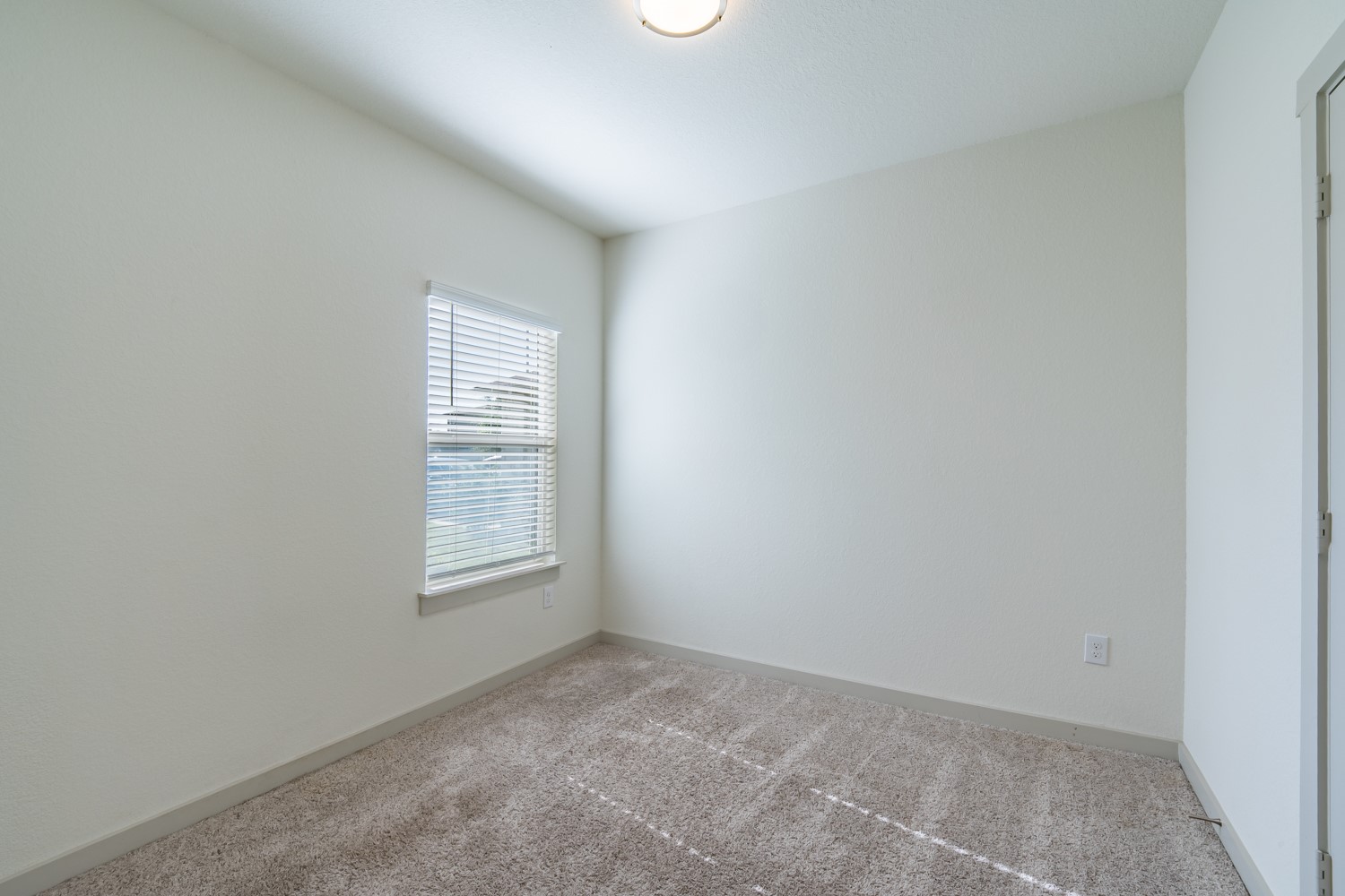 10801 Meris Lane Austin, TX 78754 - Photo 15 of 18 A well-lit bedroom with fresh carpet and a window offering natural light.