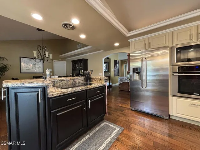 a kitchen with stainless steel appliances granite countertop a refrigerator a stove and a sink