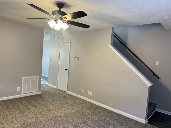 a view of an empty room with a chandelier fan